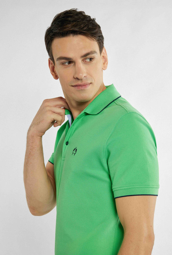 Groene polo met merklogo op de borst en zwarte fijne details