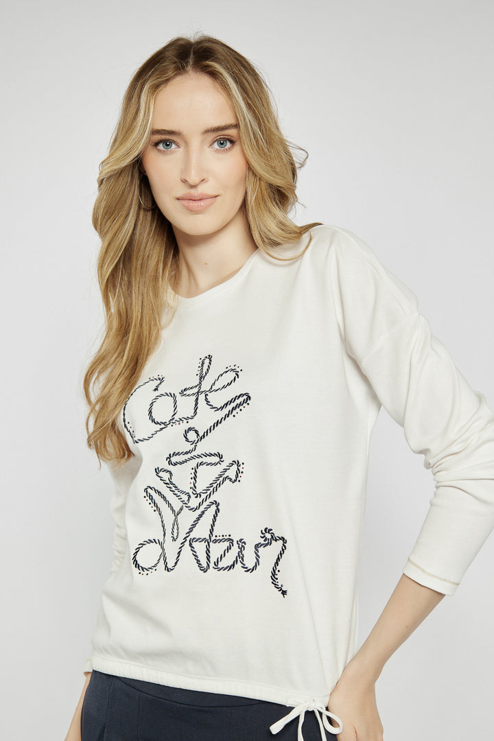 Light-colored blouse with decorative lettering on the front